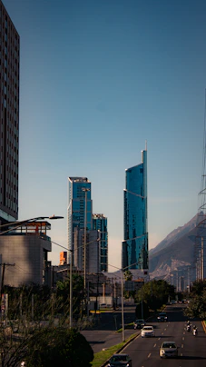 A city street with tall buildings and a mountain in the background