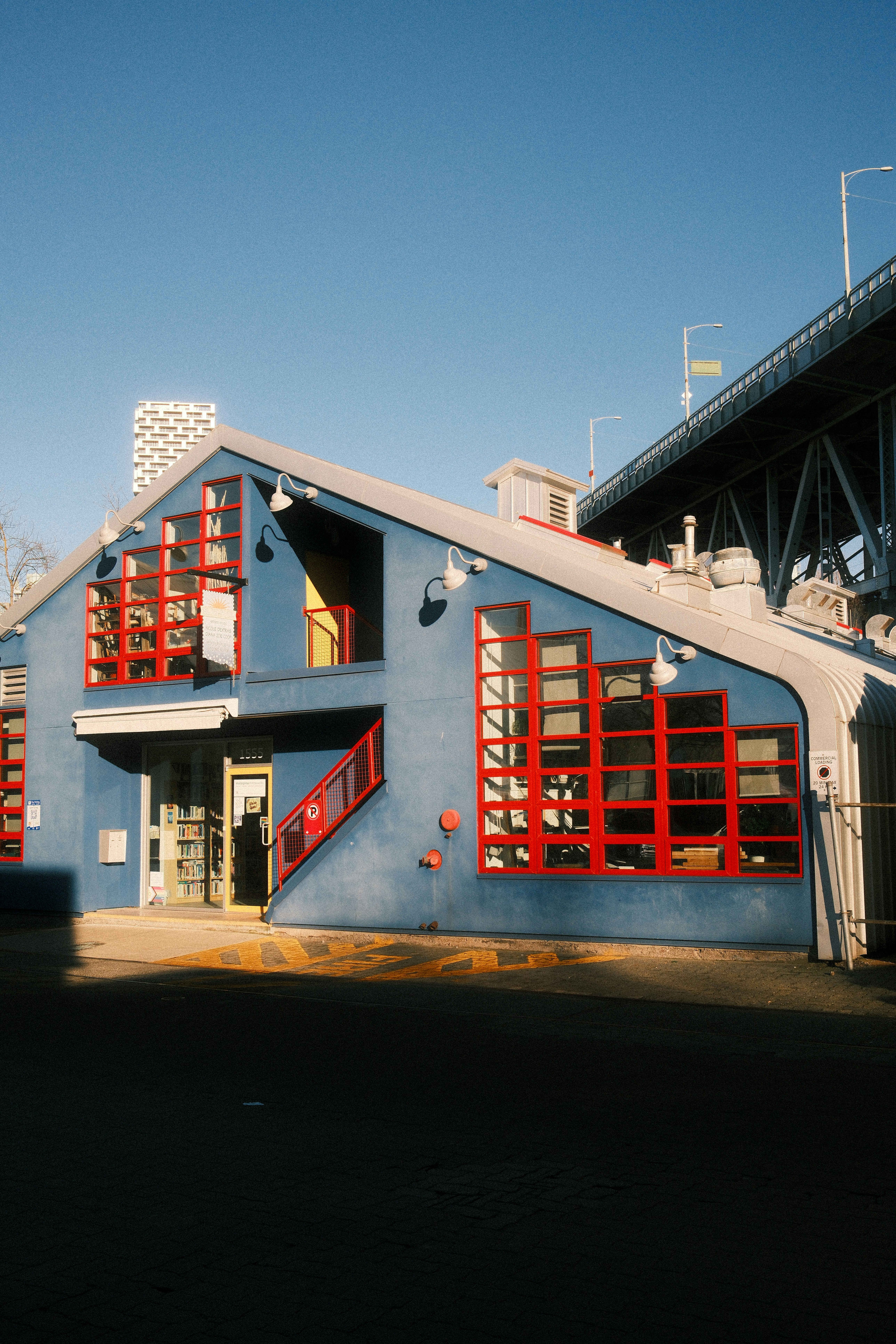 Ein großes blaues Gebäude mit roten Fenstern und einer Brücke im Hintergrund
