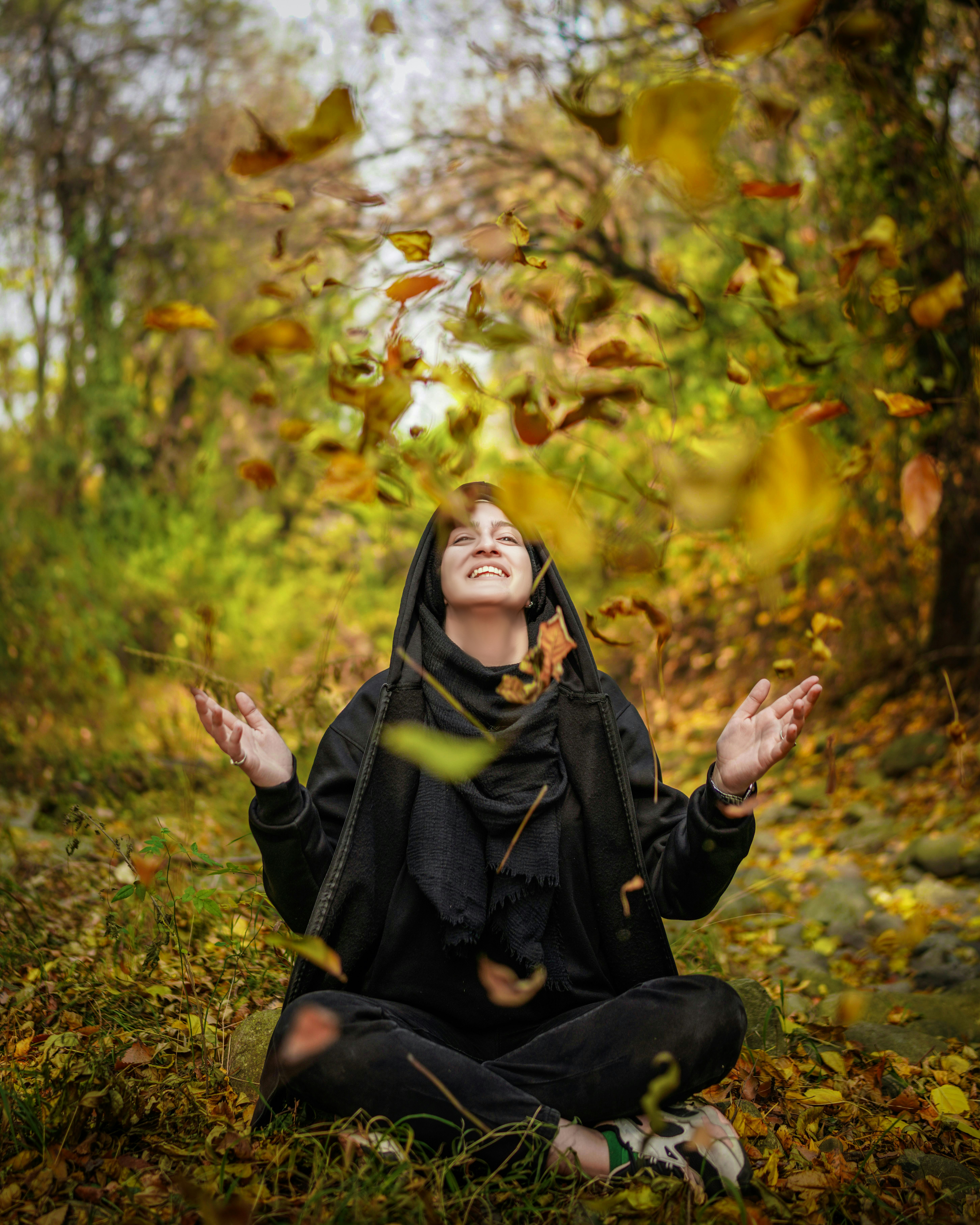 Eine Frau in einem schwarzen Outfit meditiert in einem Wald