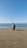 A man sitting on top of a sandy beach next to the ocean