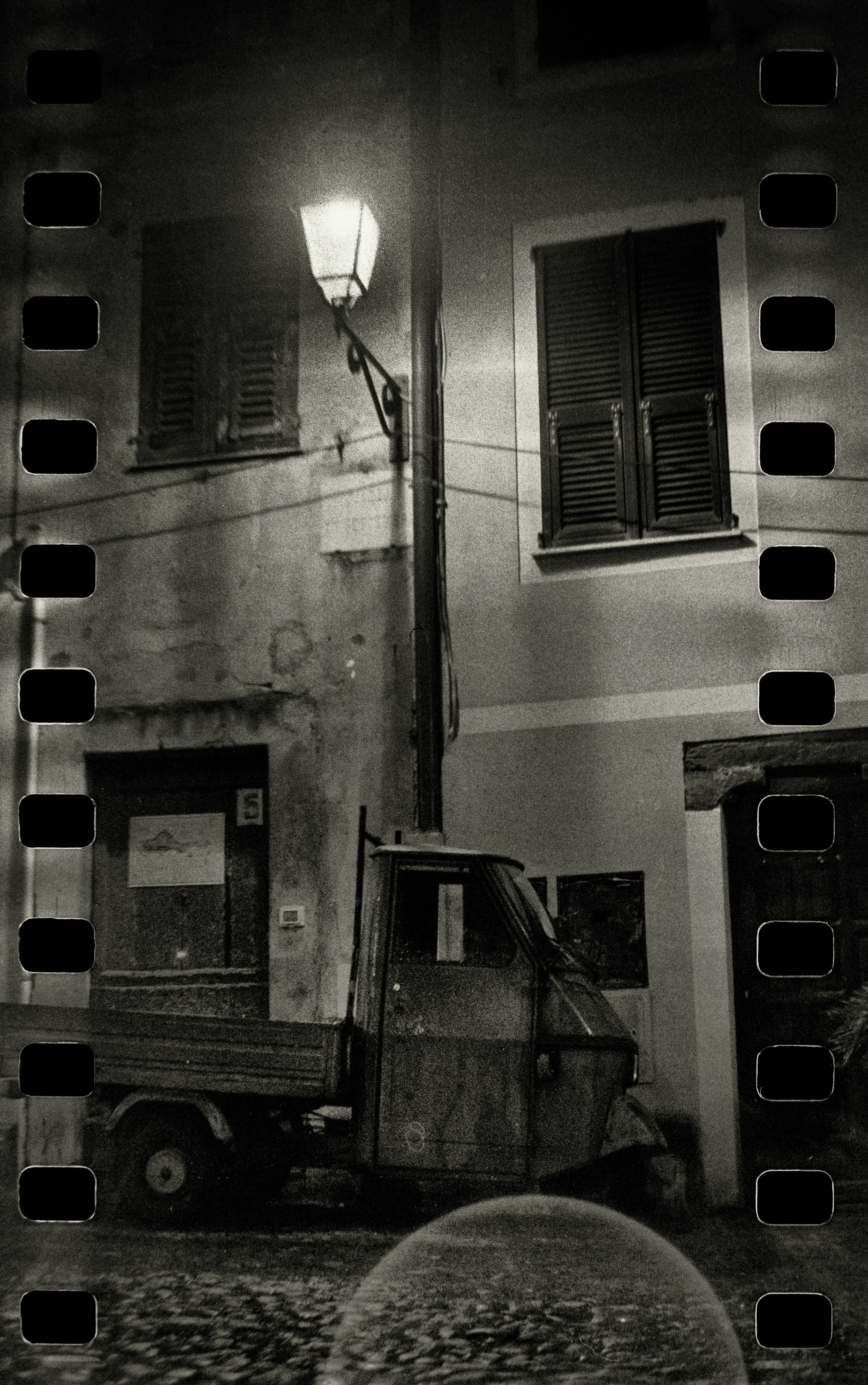 A black and white photo of a truck parked in front of a building