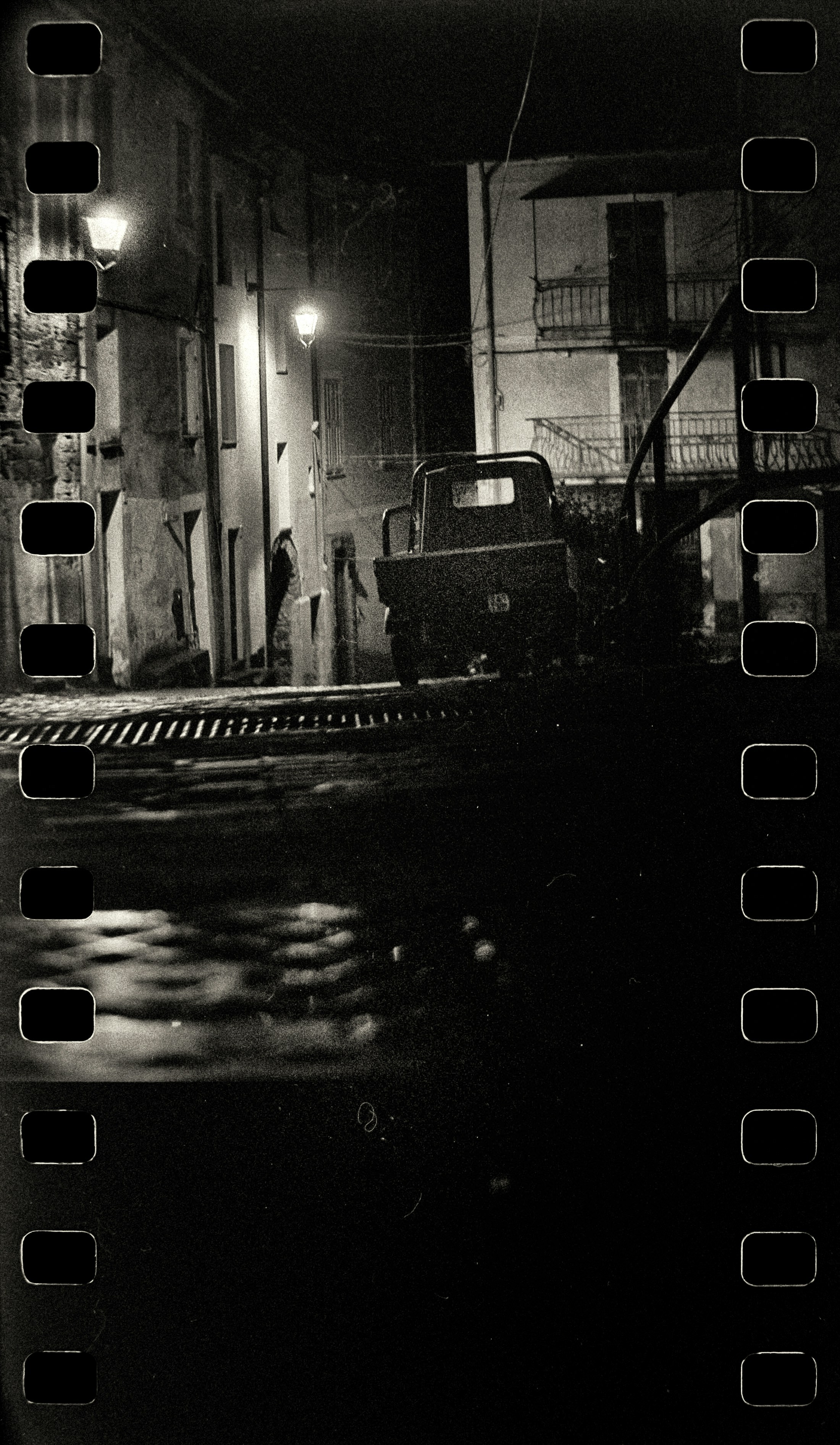 A black and white photo of a street at night