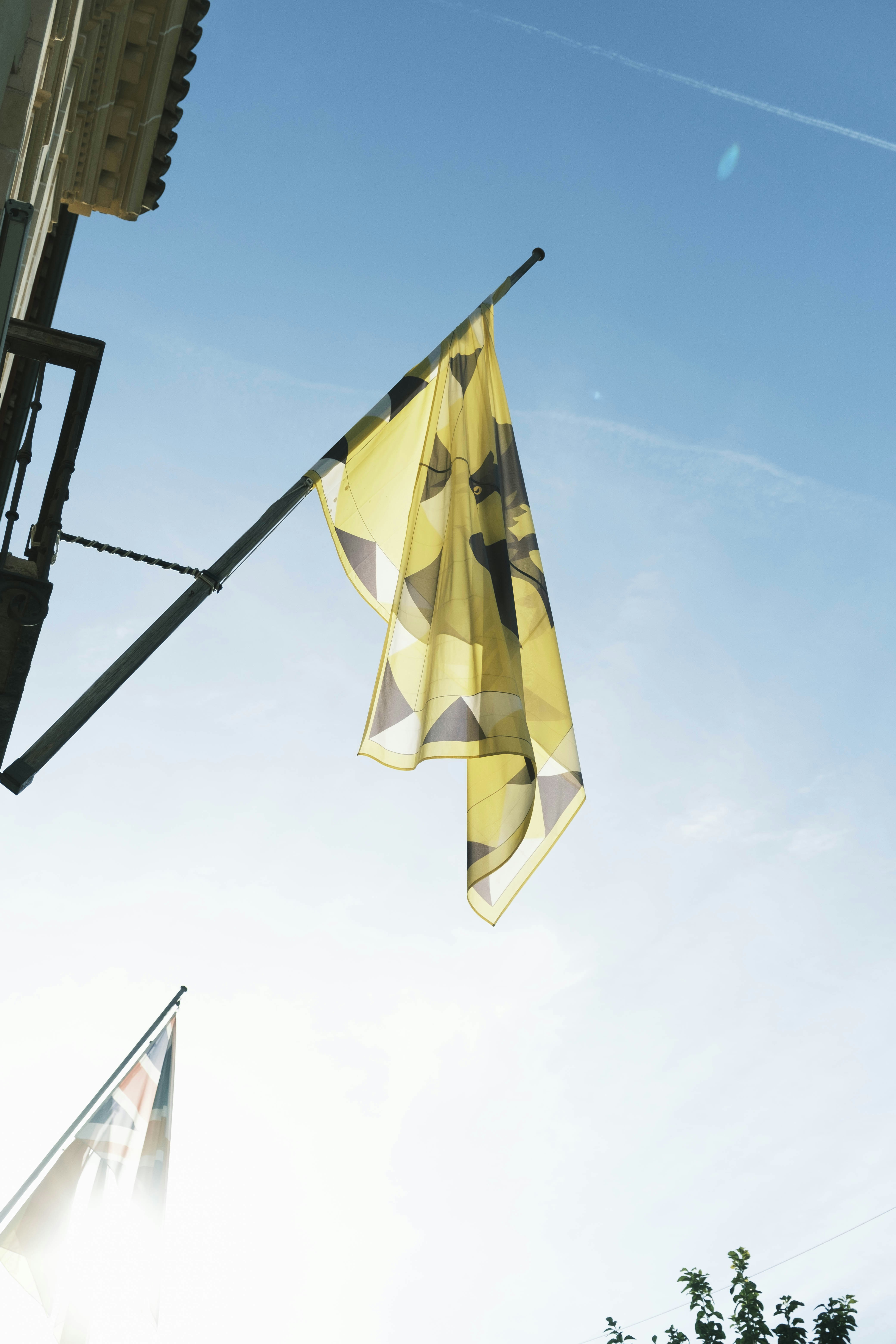 A yellow and black flag hanging from the side of a building