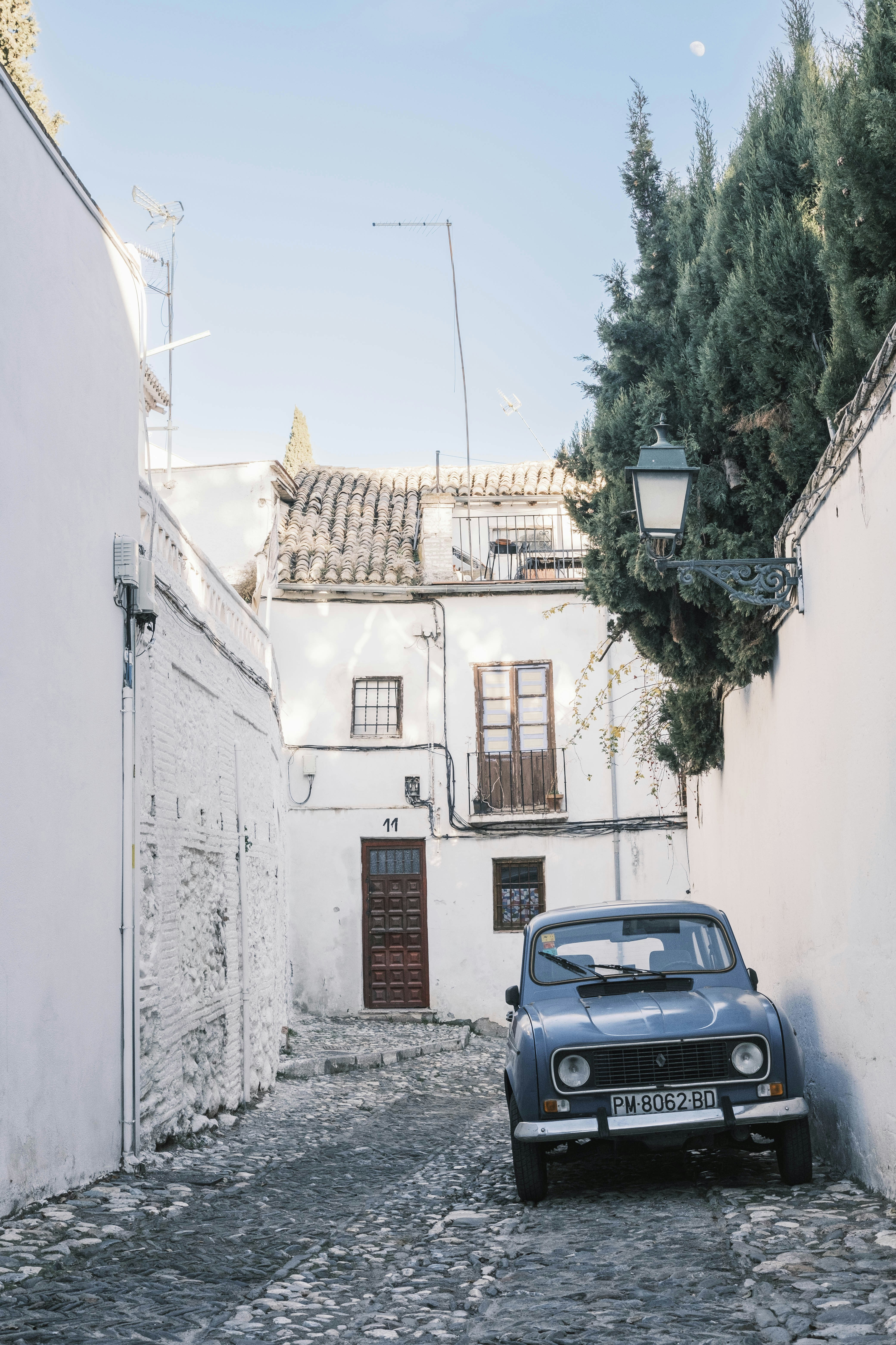 An old car parked on a cobblestone street