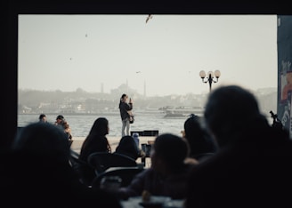 A group of people sitting at tables in front of a body of water