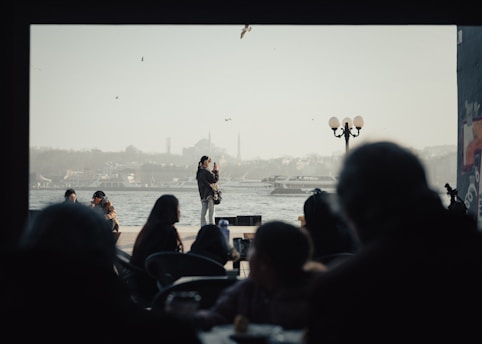 A group of people sitting at tables in front of a body of water