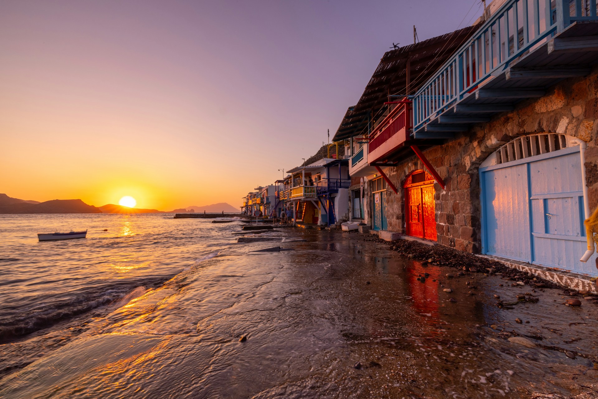 A row of houses on the beach with a sunset in the background
