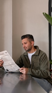 A man sitting at a table reading a newspaper