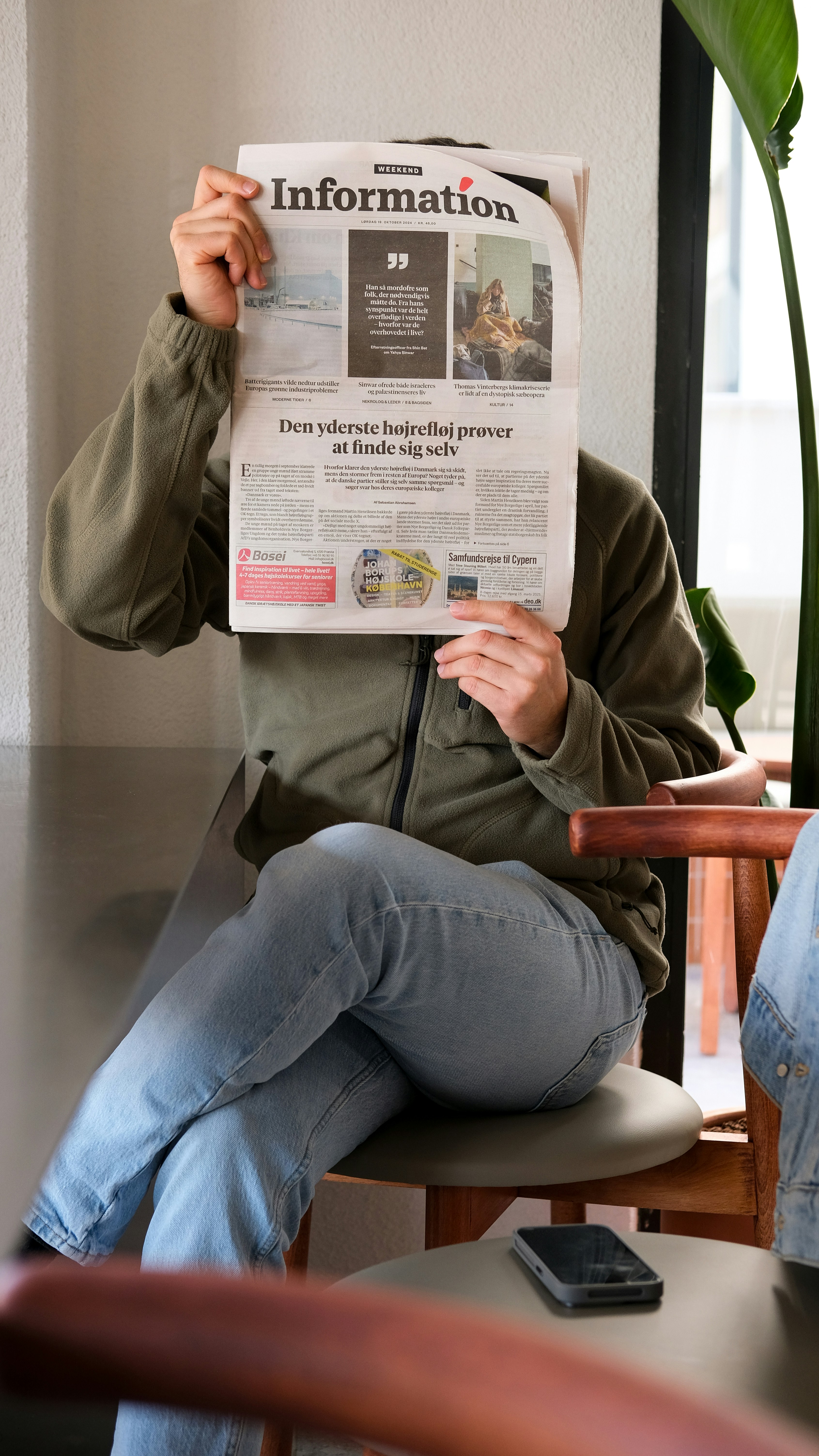 A man sitting in a chair holding up a newspaper