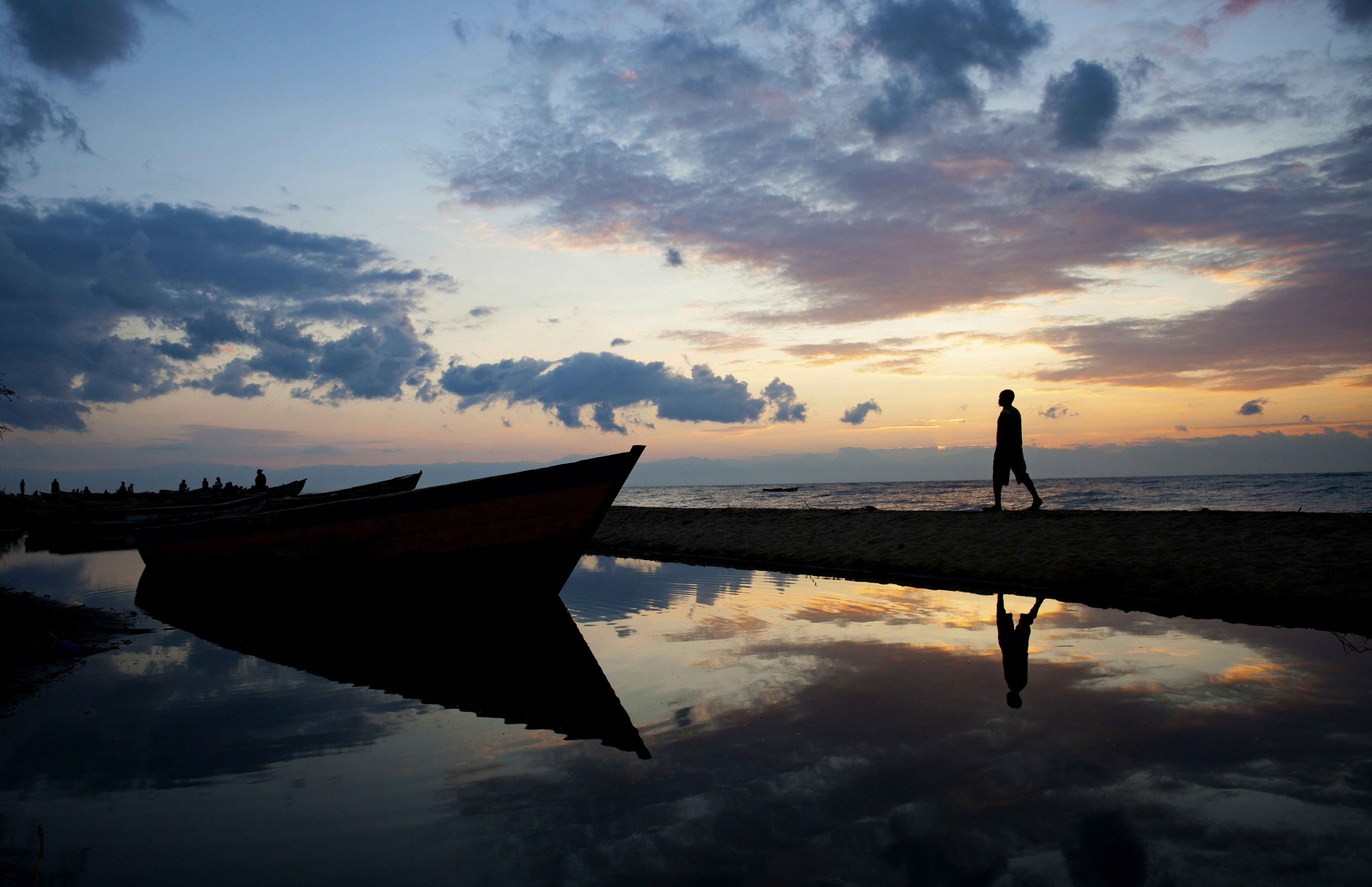 A person walking on a beach next to a boat