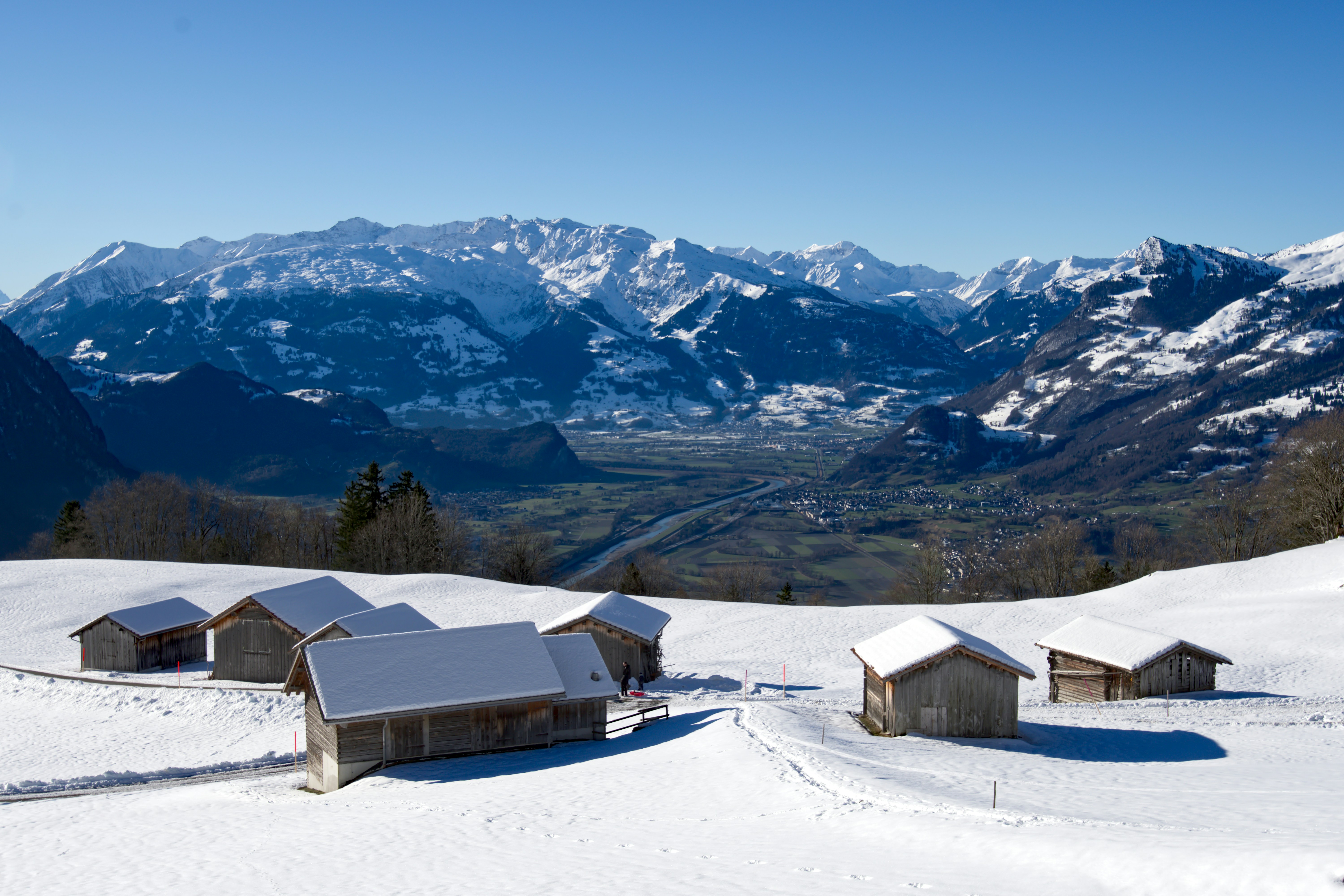 Ein schneebedeckter Berg mit ein paar Gebäuden im Vordergrund