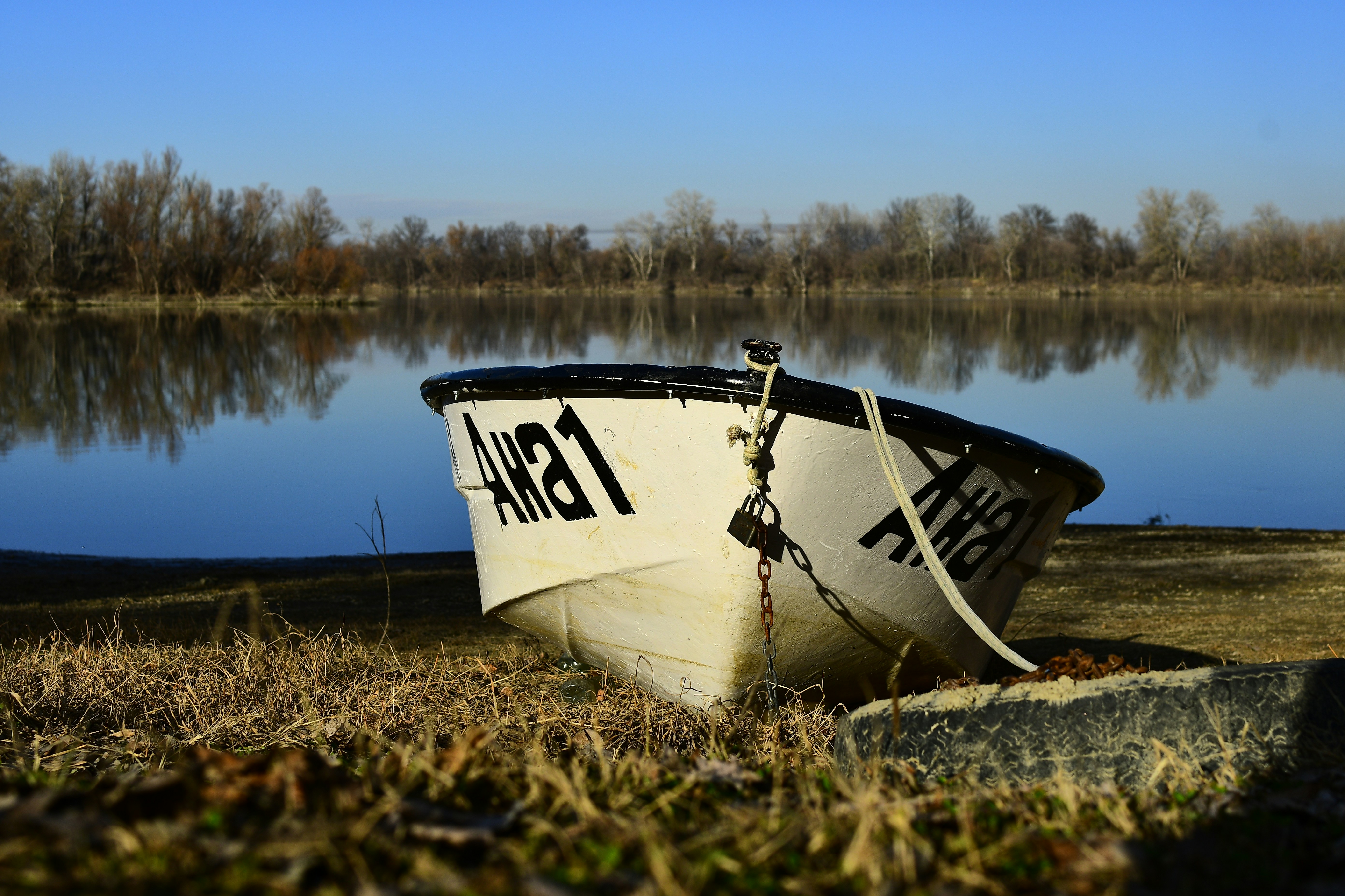 A white boat sitting on top of a grass covered field