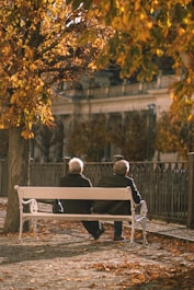 Two elderly people sitting on a bench in a park