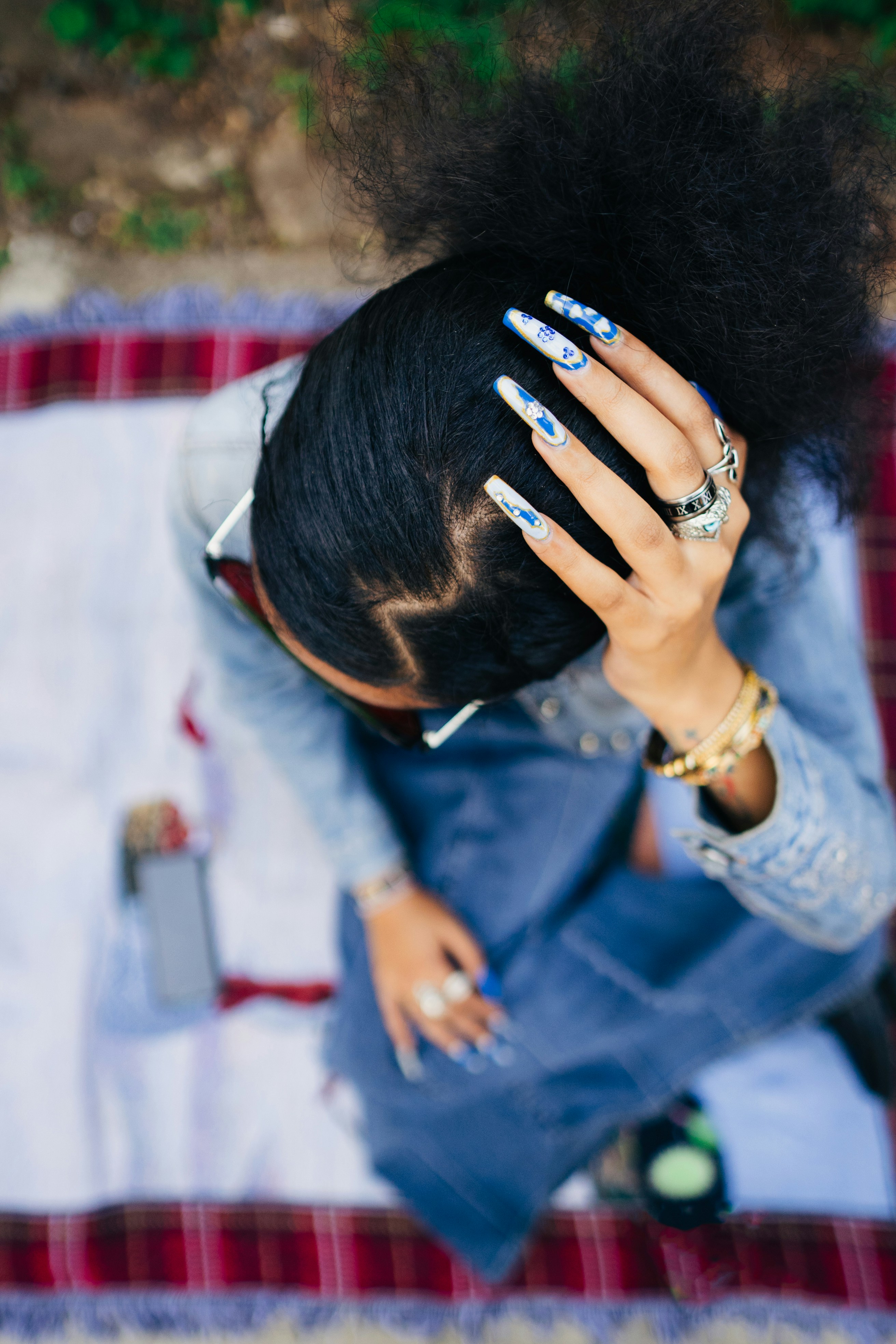 A woman sitting on a blanket with her hands on her head