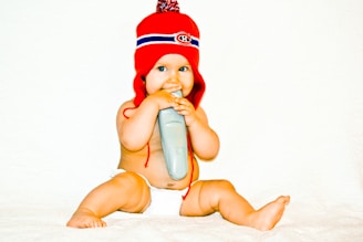 A baby in a red hat holding a toothbrush