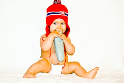 A baby in a red hat holding a toothbrush