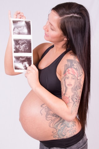 A pregnant woman holding up a picture of herself