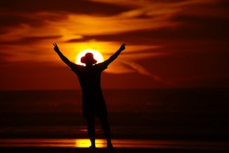 A person standing on a beach with their arms in the air
