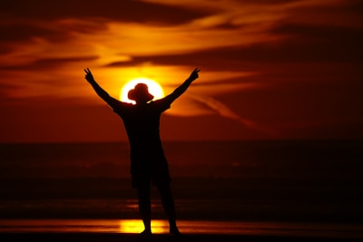 A person standing on a beach with their arms in the air
