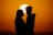 A silhouette of a couple kissing in front of the sun