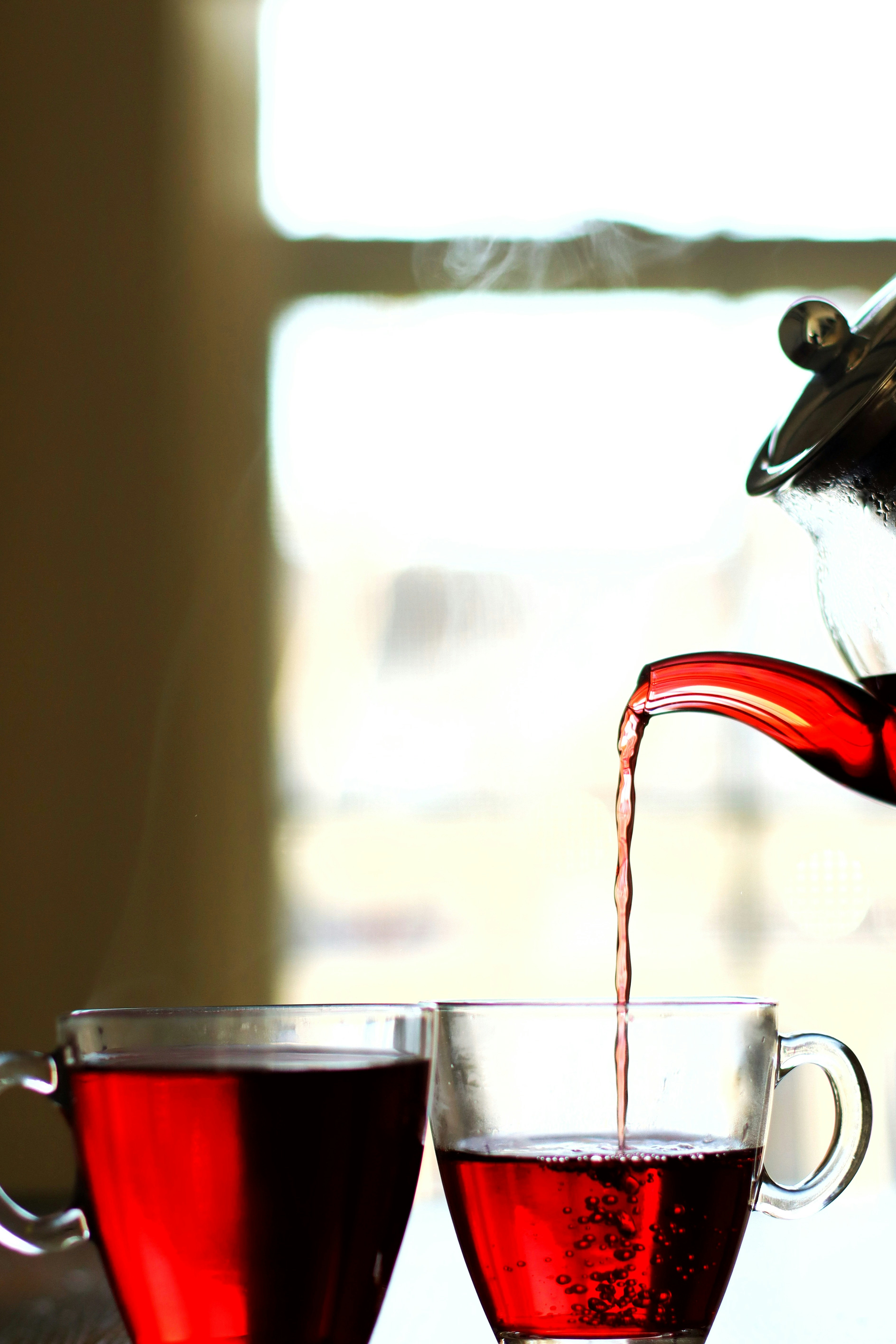 A teapot pouring tea into two cups