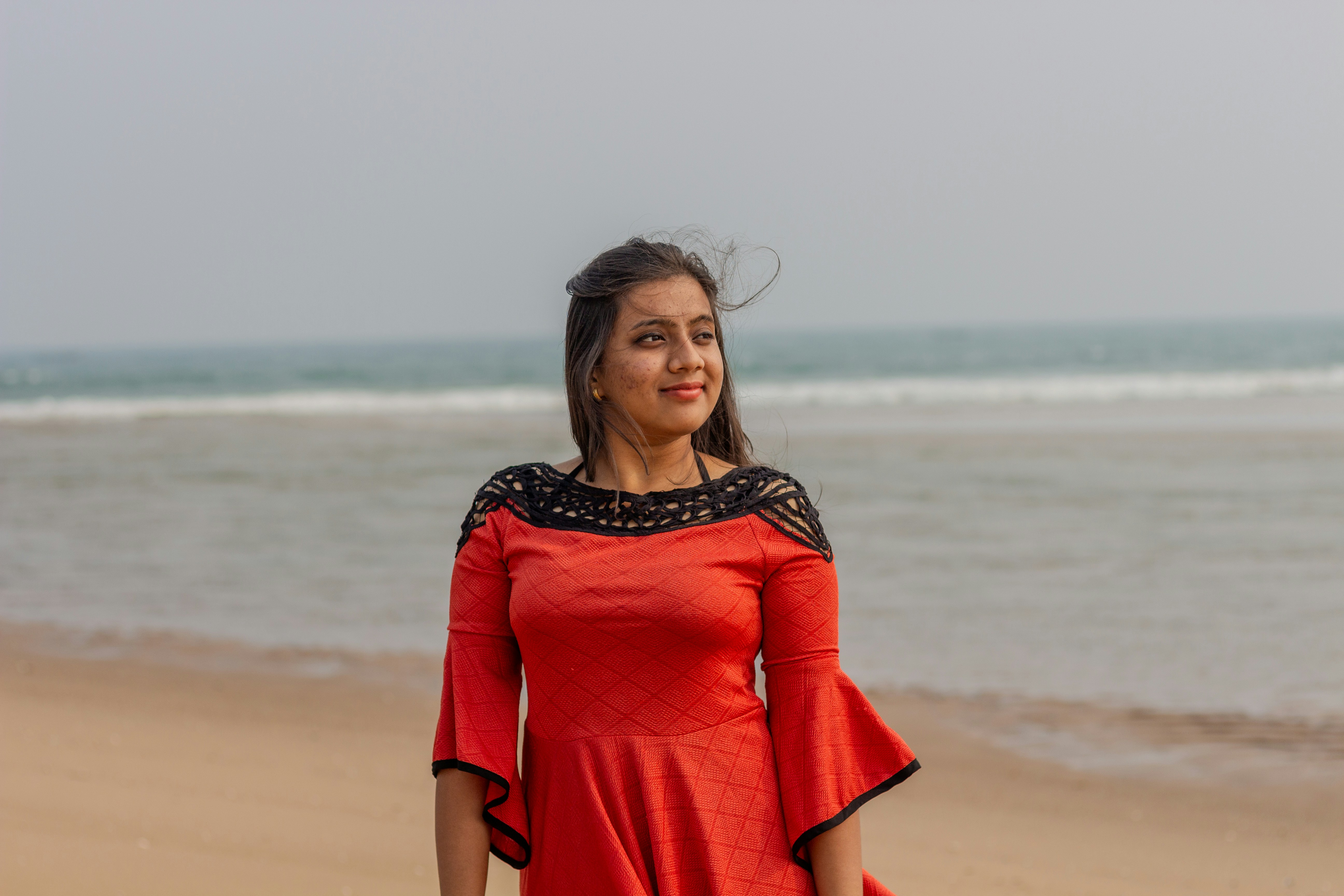 Una donna in un vestito rosso in piedi su una spiaggia