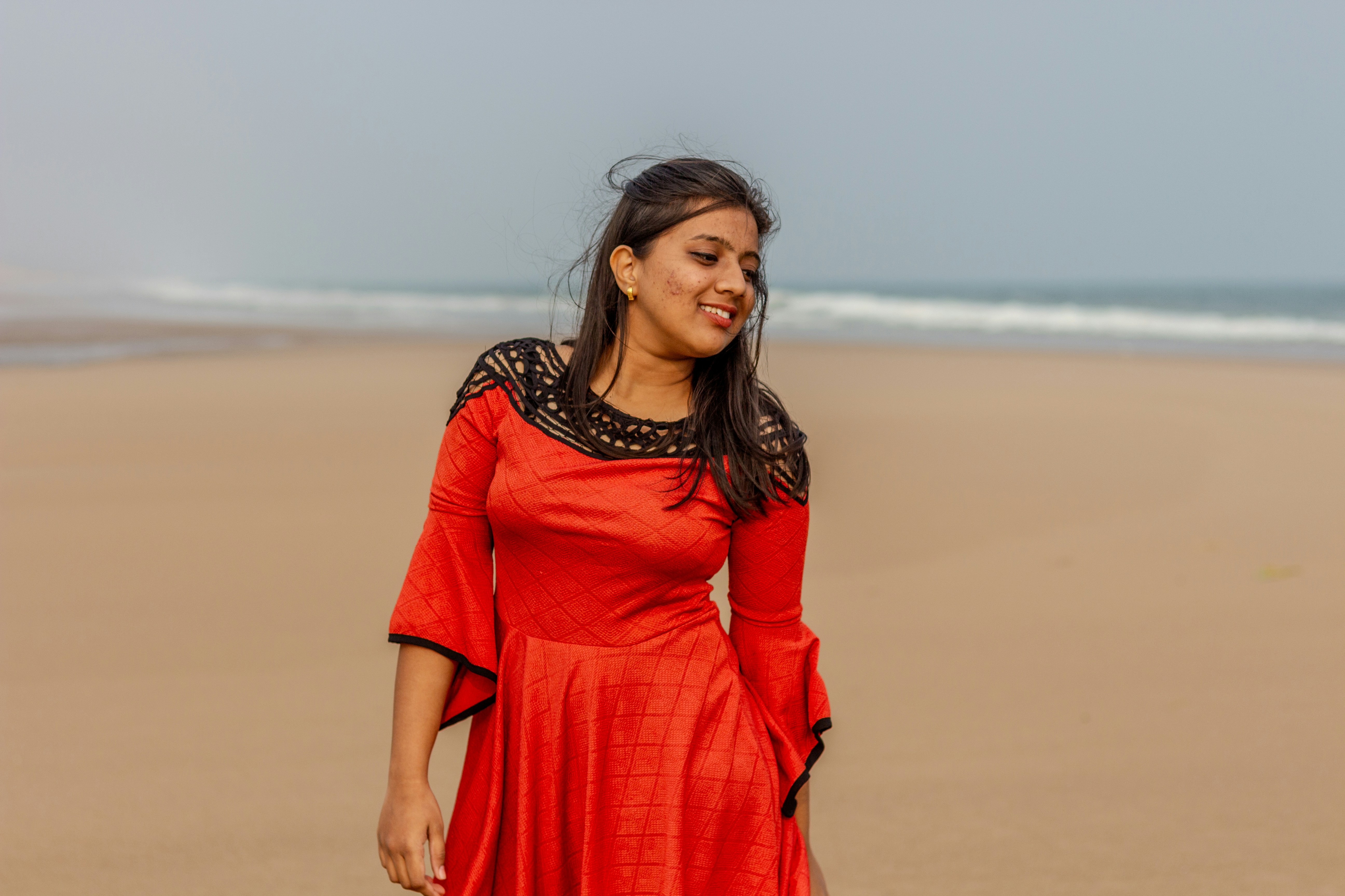 Una donna in un vestito rosso che cammina sulla spiaggia