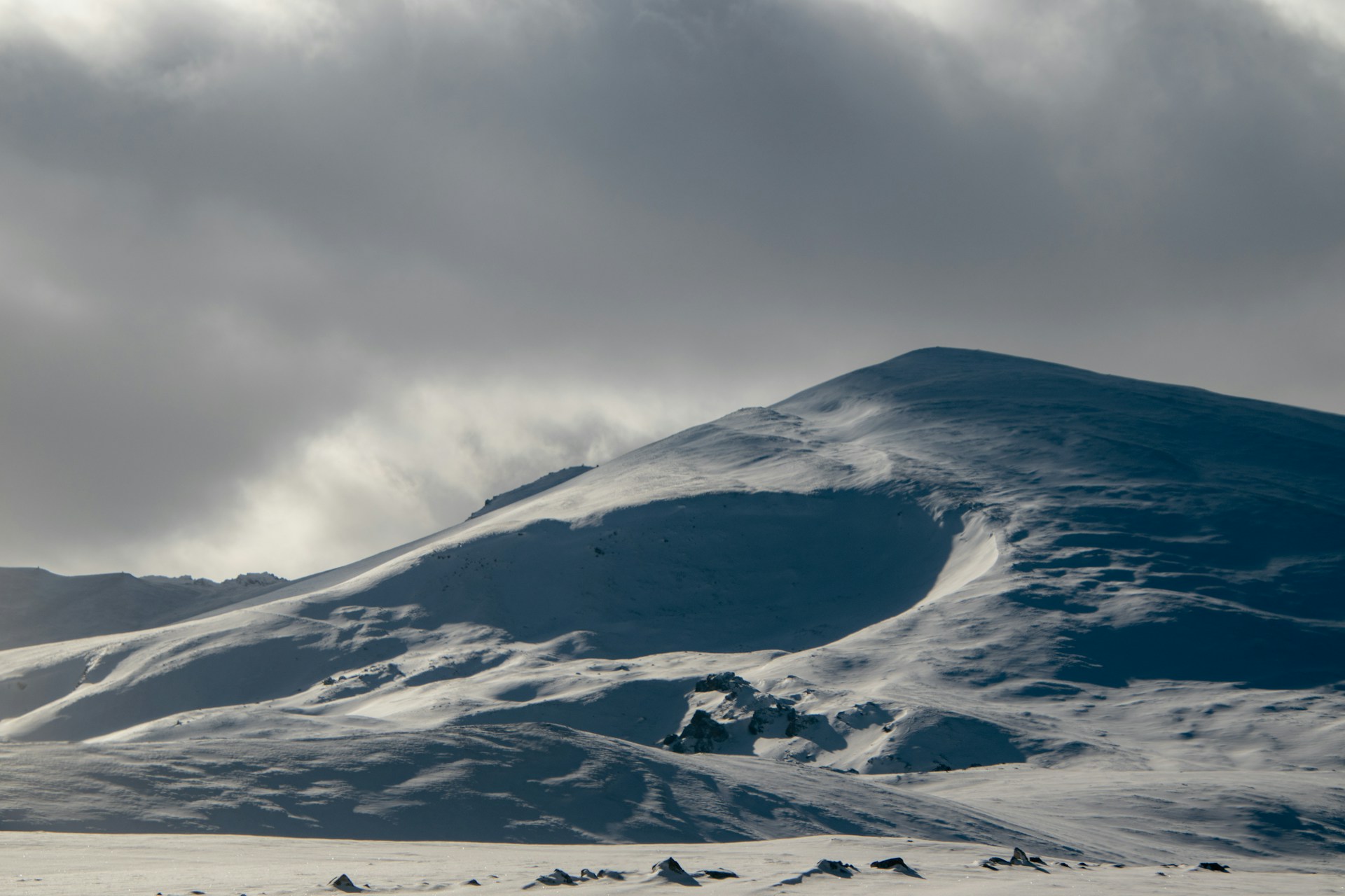 A mountain covered in snow under a cloudy sky