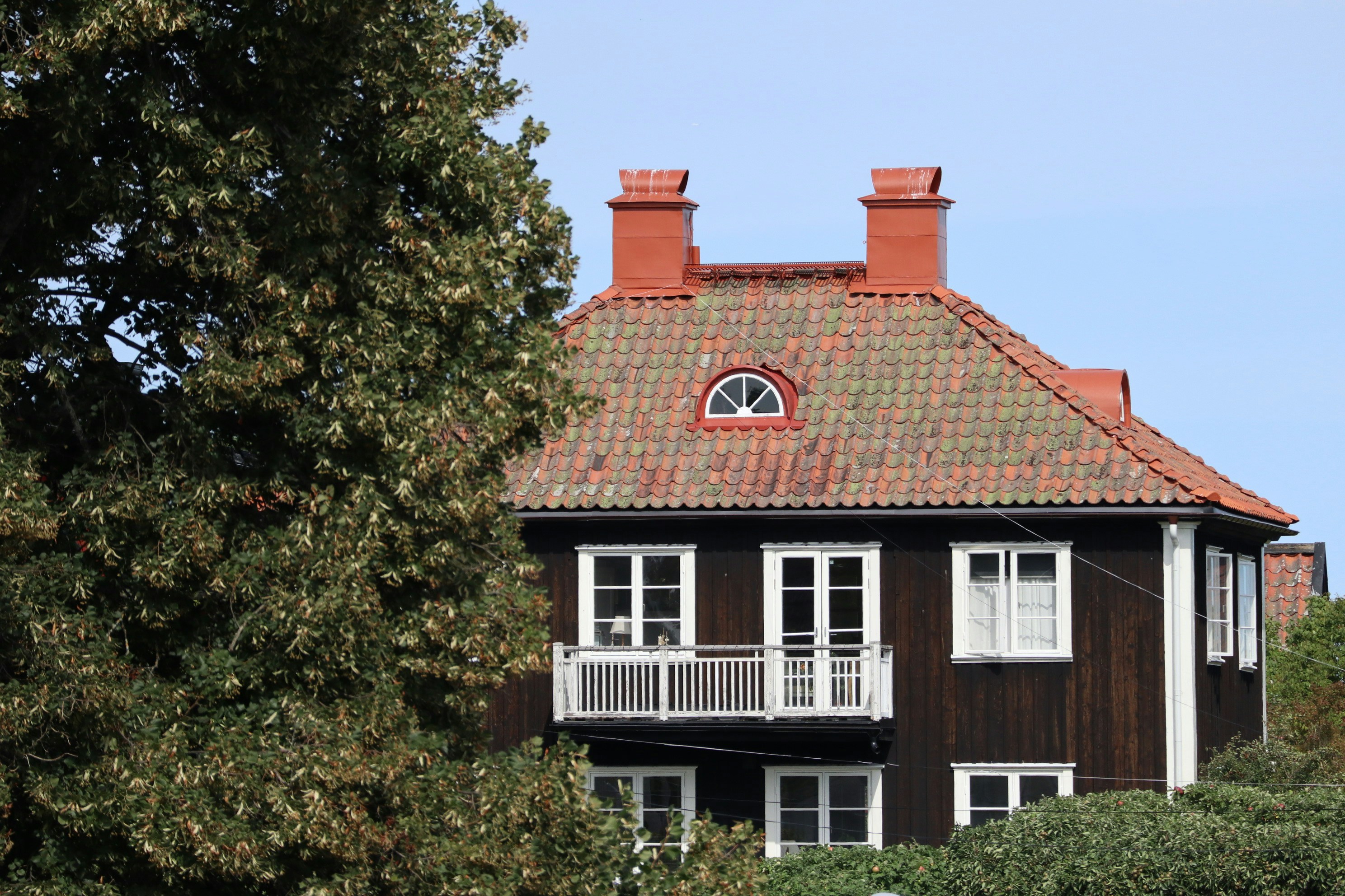 A brown house with a red roof and white windows