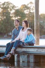 A family sitting on a dock at the water's edge