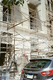 A car parked in front of a building under scaffolding