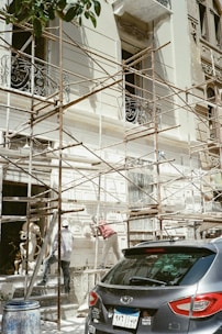 A car parked in front of a building under scaffolding