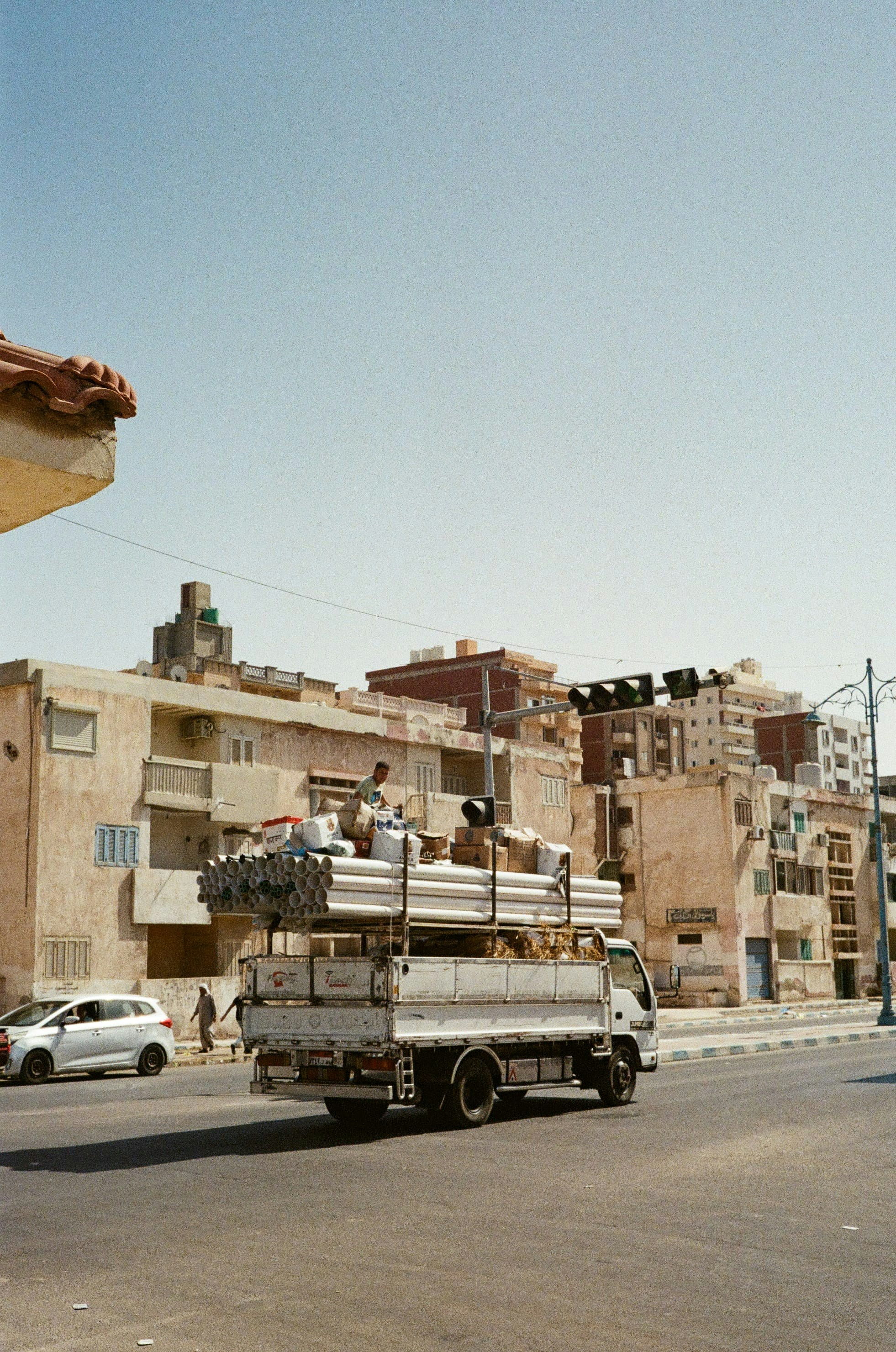A white truck driving down a street next to tall buildings