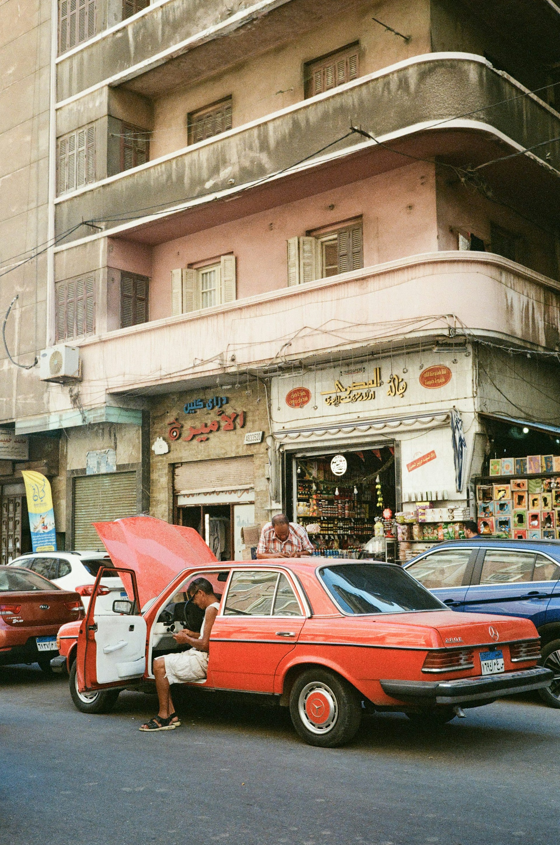 A red car parked in front of a tall building