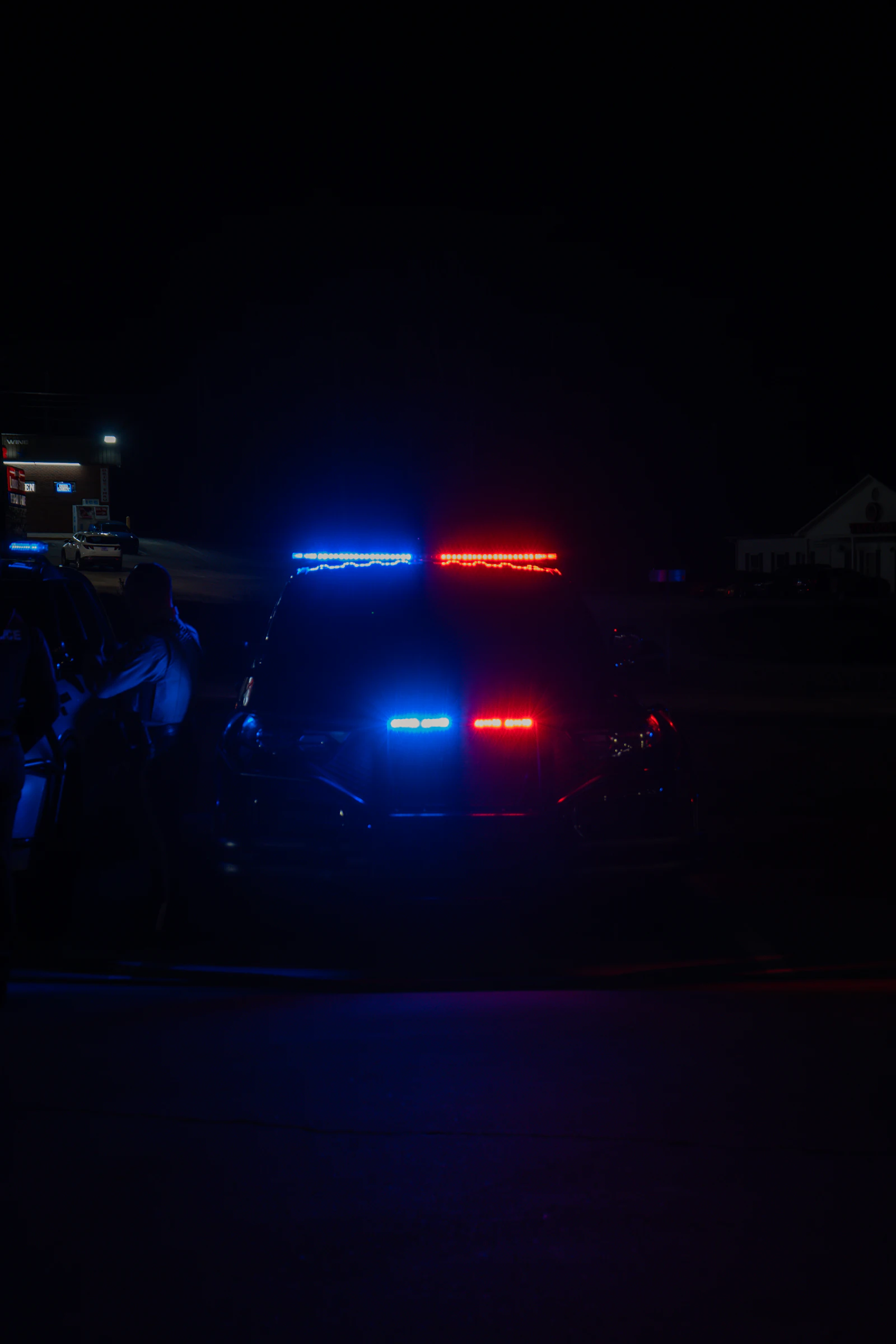 police car with red and blue lights on a dark roadside