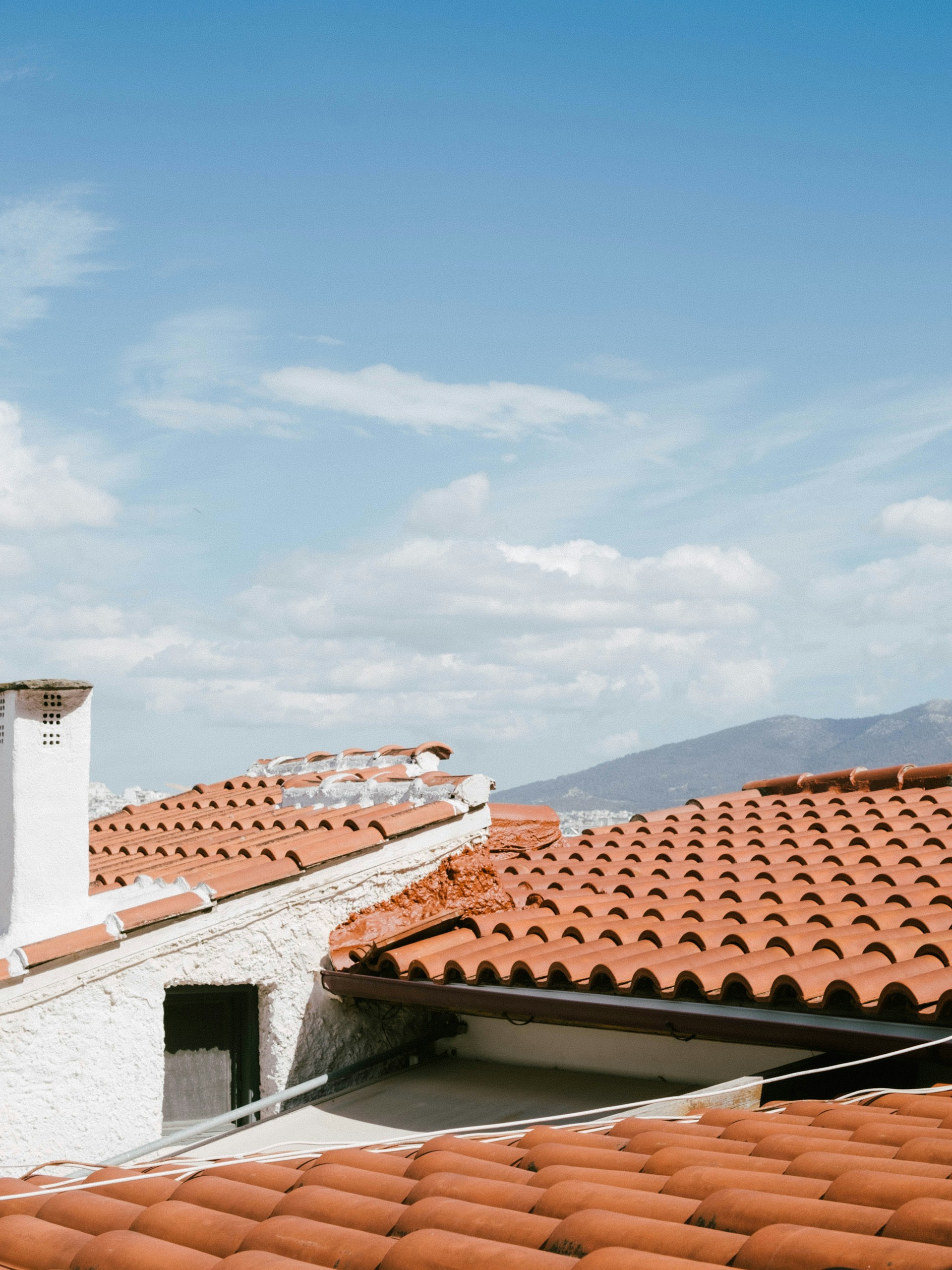 A view of a red tiled roof with a blue sky in the background