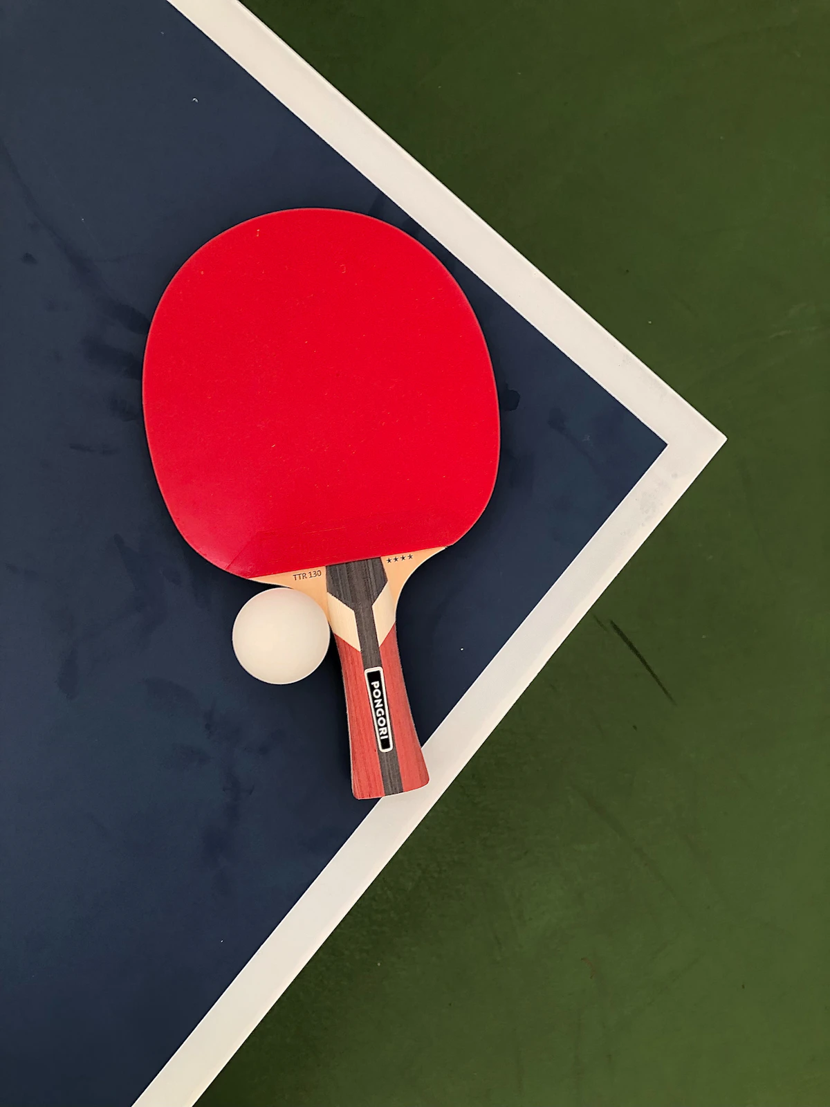 Tischtennisschläger und Ball auf blau-grüner Fläche