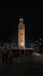 A group of people standing in front of a tall clock tower