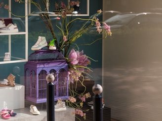 A purple birdcage with flowers on a table
