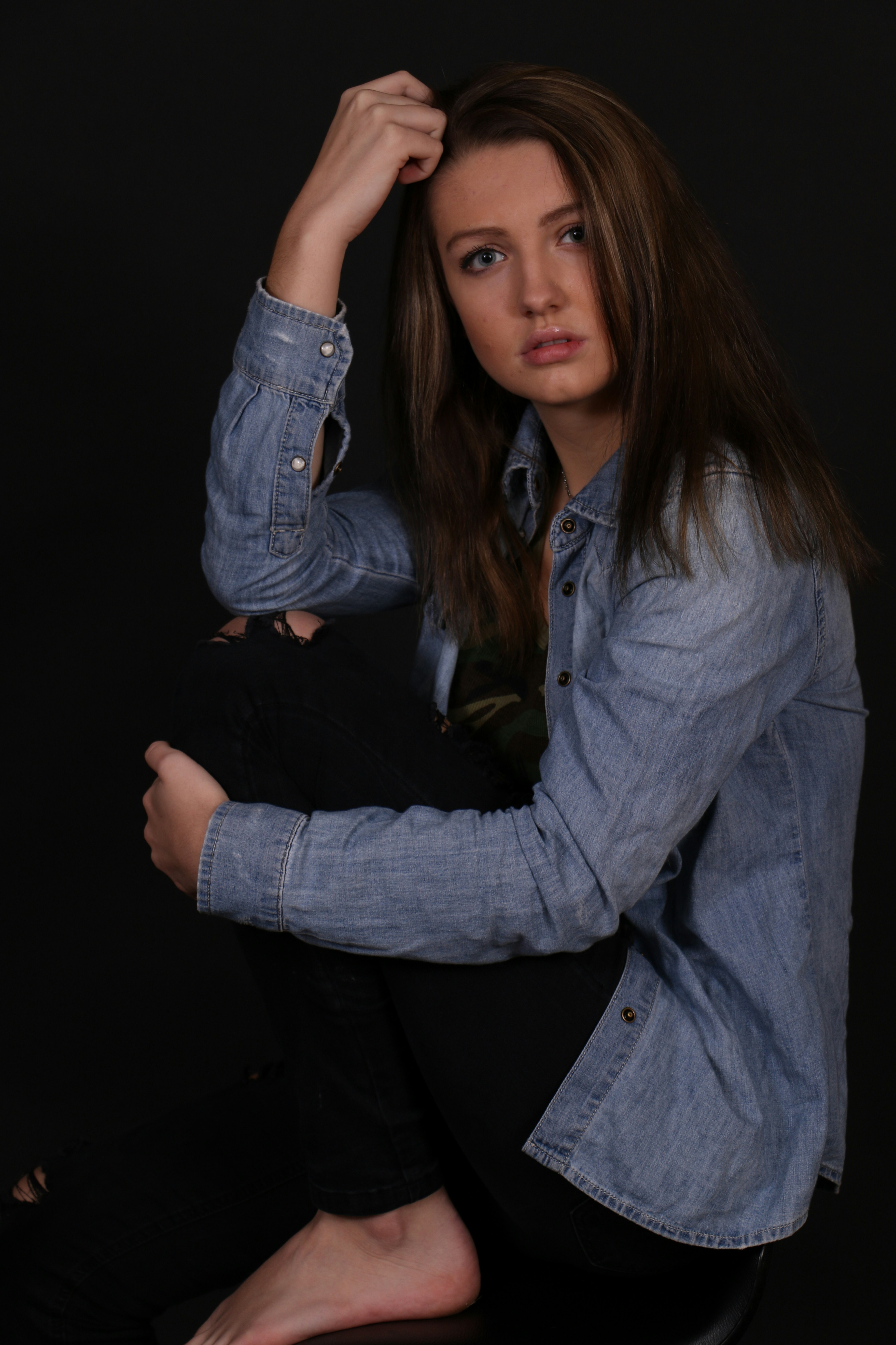 A woman sitting on a chair with her hand on her head