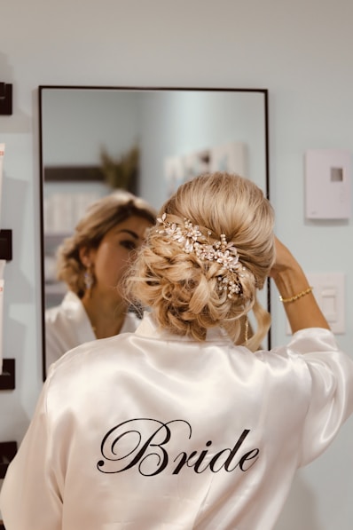 A woman in a bridal robe looking at herself in a mirror