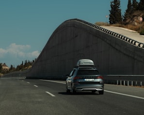A car driving down a road next to a hill