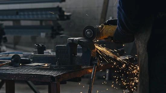 A person using a grinder on a piece of metal