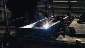 Welder working on a piece of metal in a factory