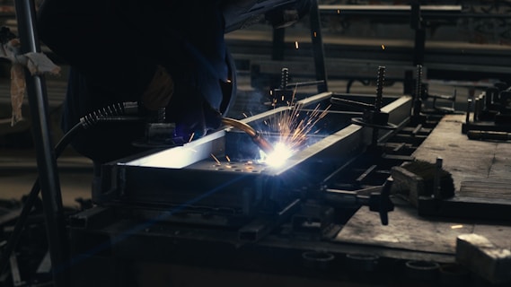 Welder working on a piece of metal in a factory