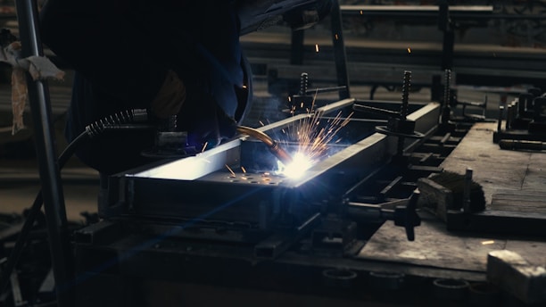 Welder working on a piece of metal in a factory