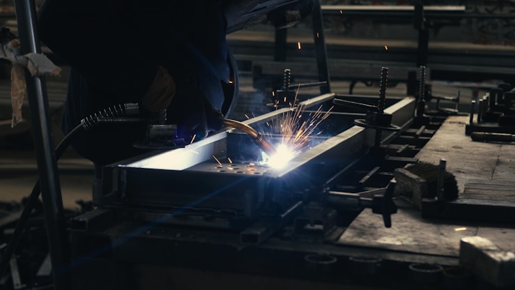 Welder working on a piece of metal in a factory