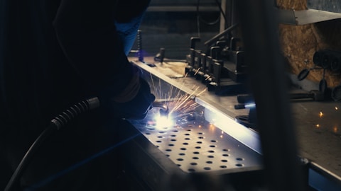 A man welding a piece of metal in a factory