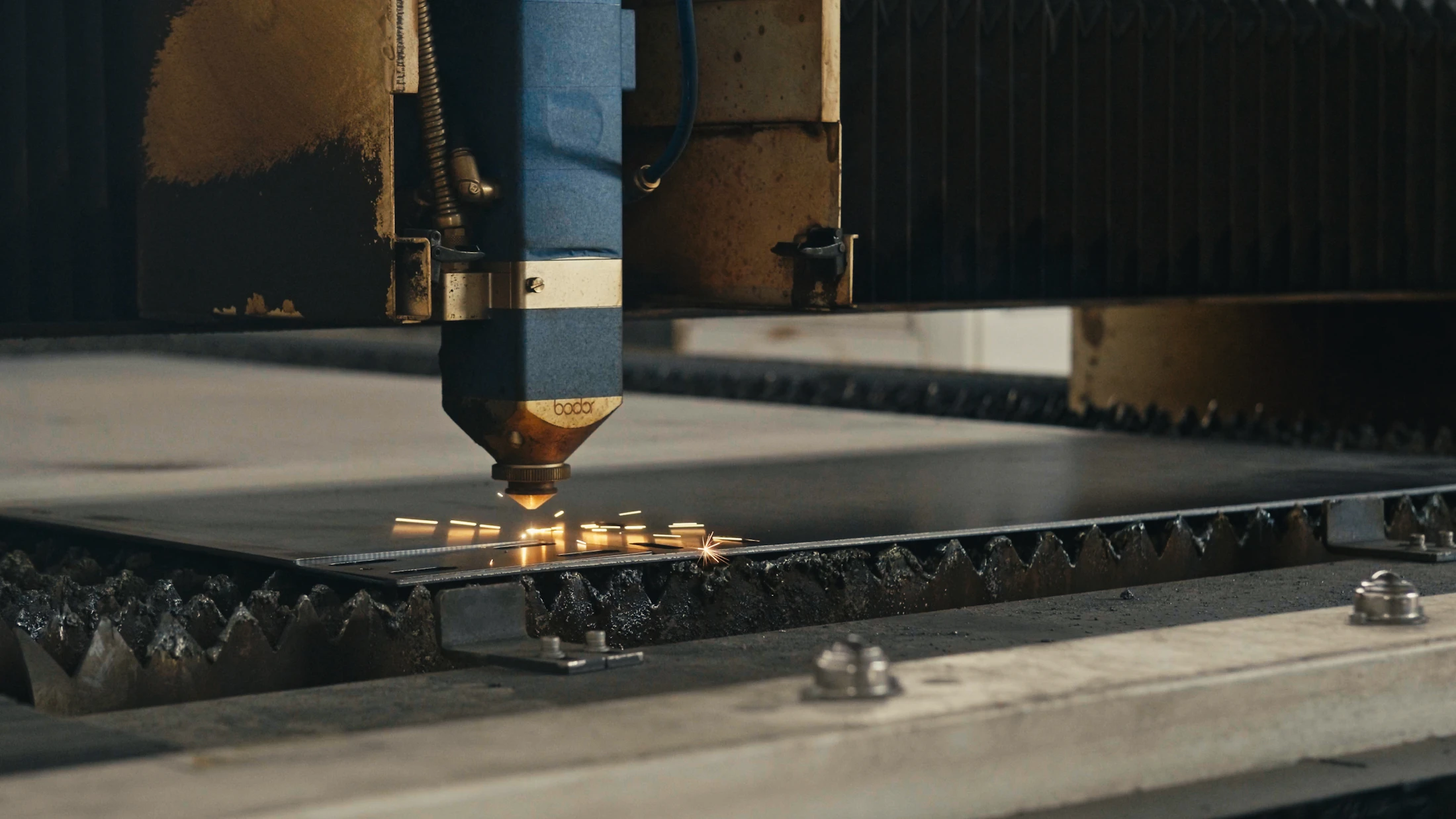 Máquina de corte a laser cortando chapa metálica com faíscas em ambiente industrial