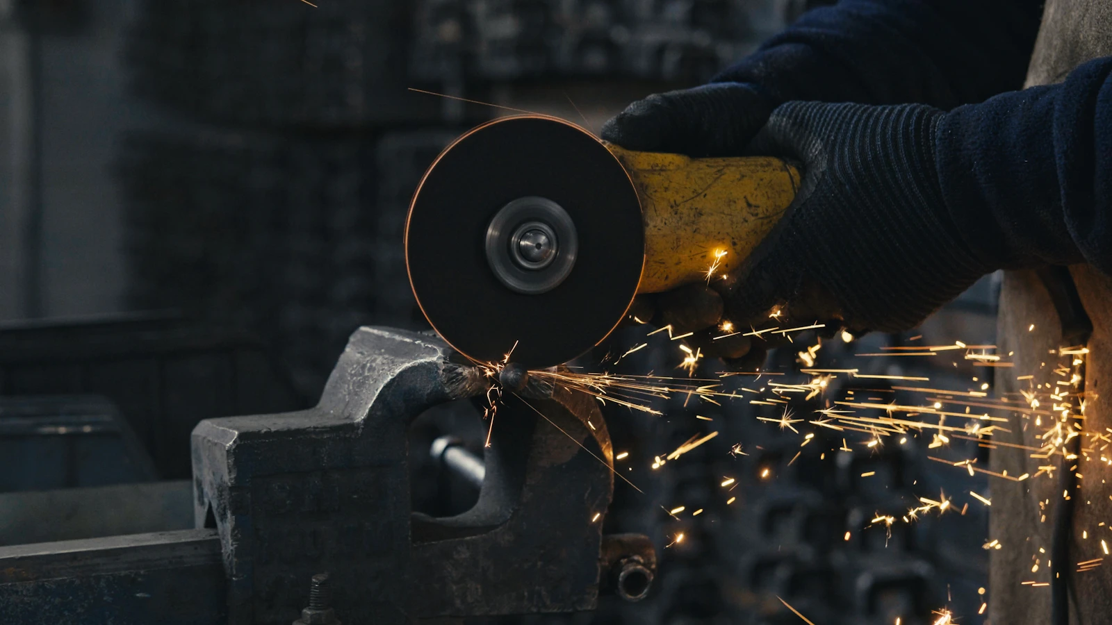 A trainee using an angle grinder on a metal piece, sparks streaming